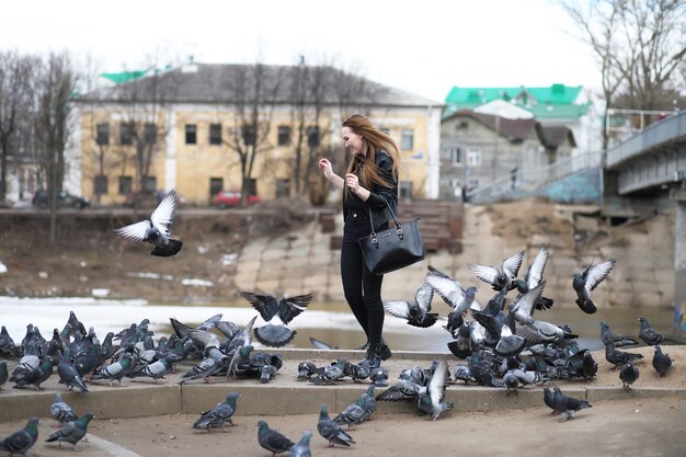 Une fille en promenade dans le parc et un troupeau de pigeons