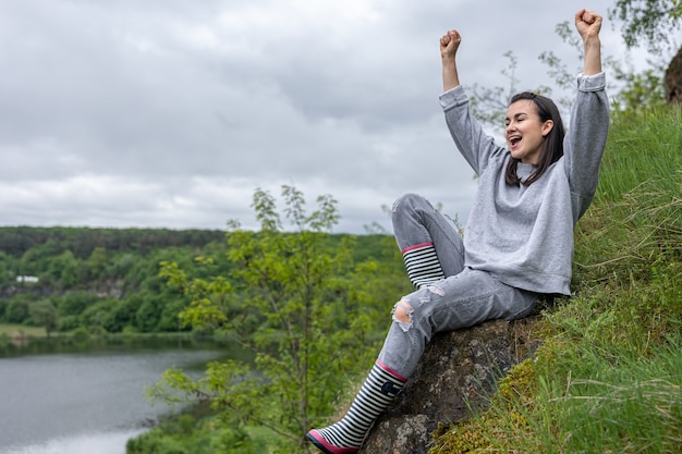 Une fille en promenade a gravi une montagne dans une région montagneuse et se réjouit