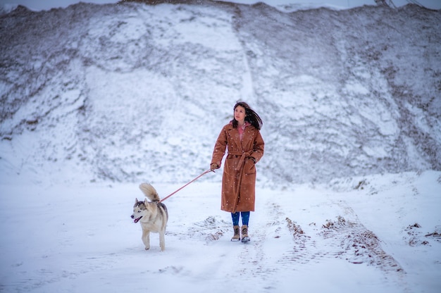 Une fille promène son chien à travers la forêt d'hiver