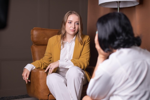 Une fille psychologue écoute un client assis dans un fauteuil