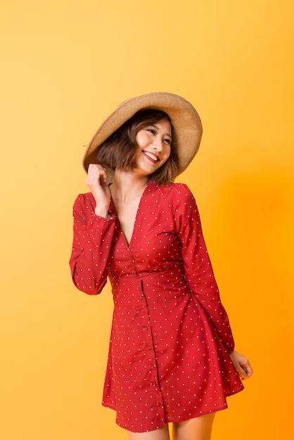 Fille puissante en robe rouge portant un chapeau posant se détendre sur fond orange