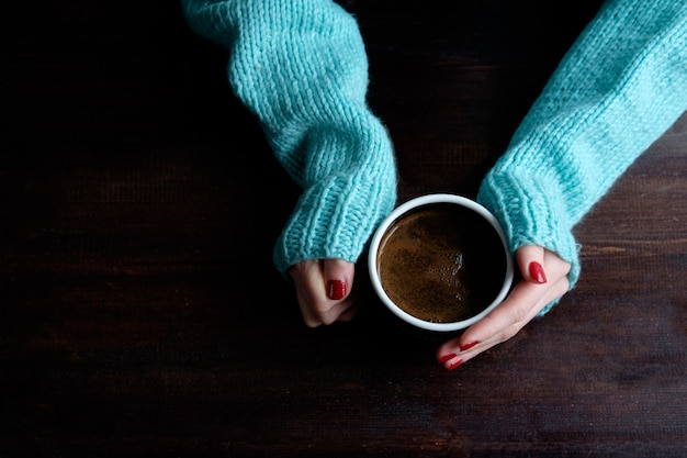 Fille en pull bleu tenant la tasse de café closeup mains