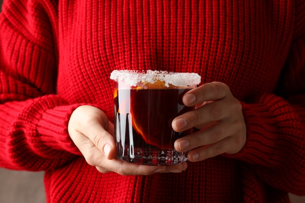 Fille en pull rouge tenant le verre de vin chaud, Close up