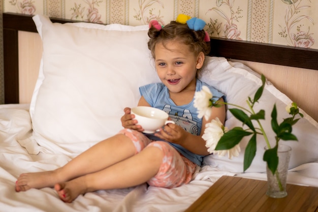 fille en pyjama et bigoudis sur le lit