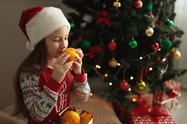 une fille en pyjama du nouvel an une fille renifle une orange