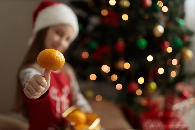 une fille en pyjama du nouvel an une fille tient une orange