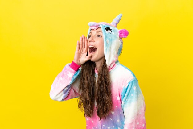 Fille avec pyjama licorne sur fond isolé criant avec la bouche grande ouverte sur le côté