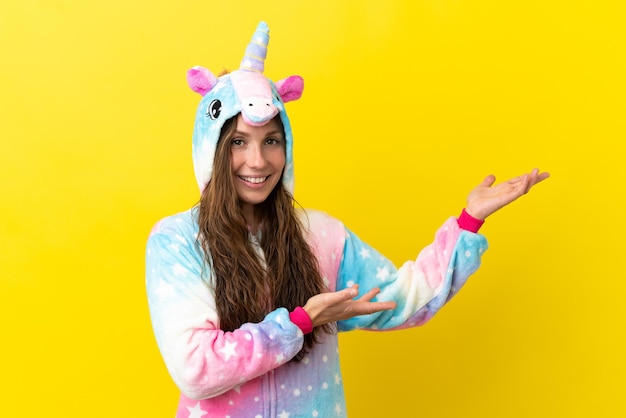 Fille avec un pyjama de licorne sur fond isolé tendant les mains sur le côté pour inviter à venir