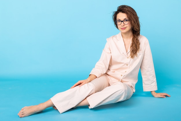 Fille en pyjama posant tout en se reposant à la maison sur fond bleu