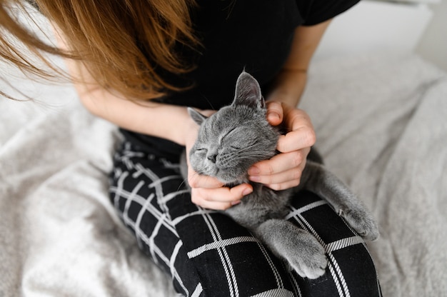 fille en pyjama tient son animal de compagnie bien-aimé dans ses bras. Chaton écossais dans les bras de la jeune fille.