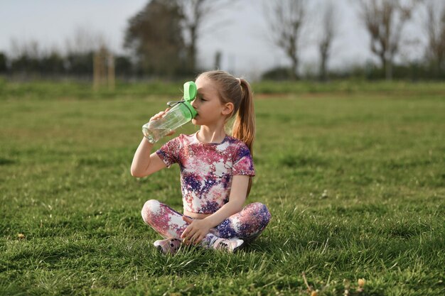 Une fille qui boit de l'eau au stade