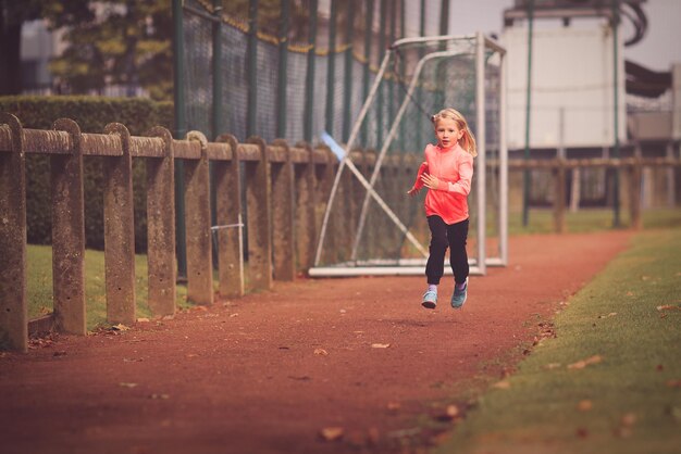 Photo une fille qui court sur un terrain de football.