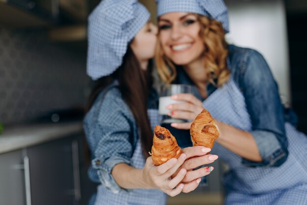 Fille Qui Embrasse Sa Mère. Ils Tiennent Un Croissants Et Le Montrent Sur Les Mains Droites