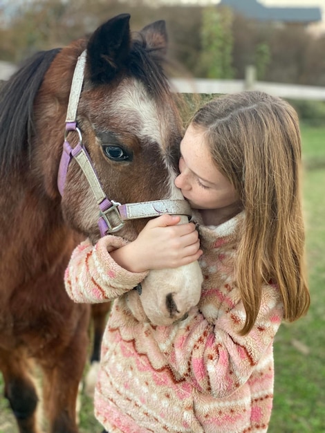 Une fille qui embrasse son poney.