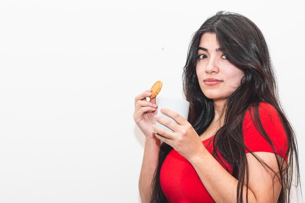 Fille qui est heureuse et tient un cookie et une tasse de café dans ses mains