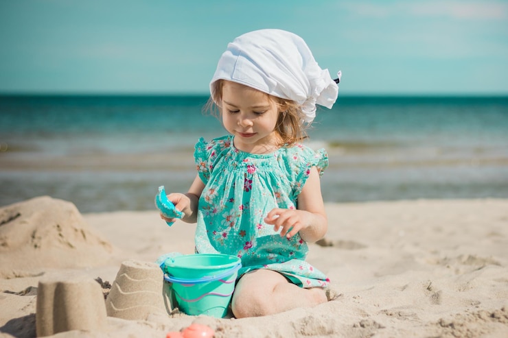 Photo une fille qui fait des châteaux de sable assise sur la plage.