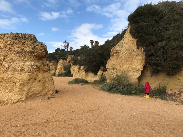 Photo une fille qui marche sur des formations rocheuses à la plage.