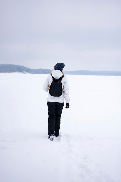 Fille qui marche sur un lac d'hiver enneigé