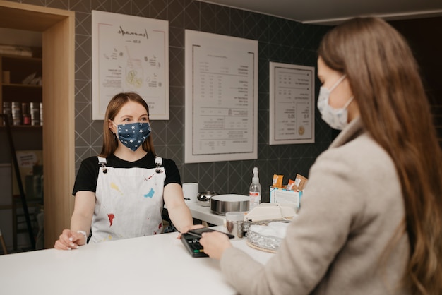 Une fille qui porte un masque facial utilise un smartphone pour payer