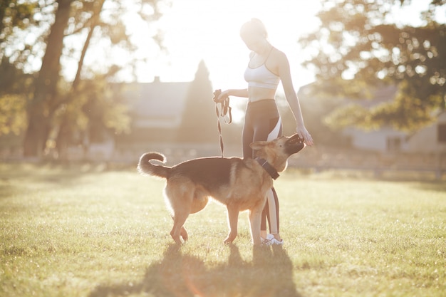 Fille qui promène son chien au lever du soleil