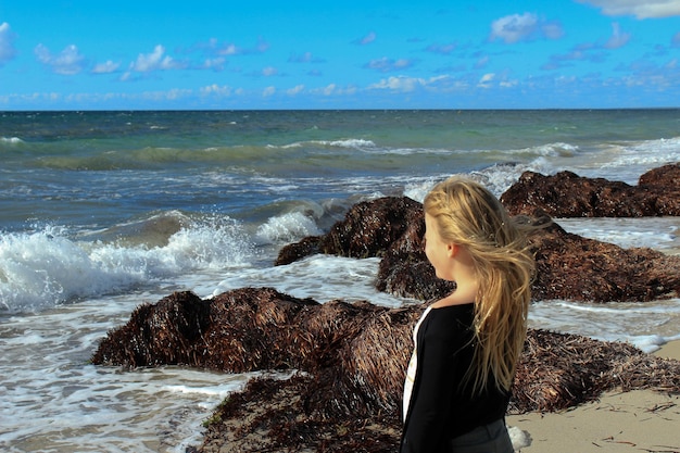 Photo une fille qui regarde la mer contre le ciel.