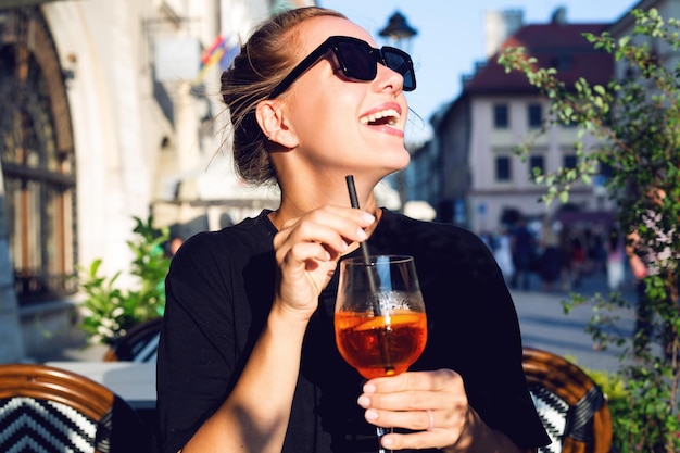 Fille qui rit en buvant un cocktail