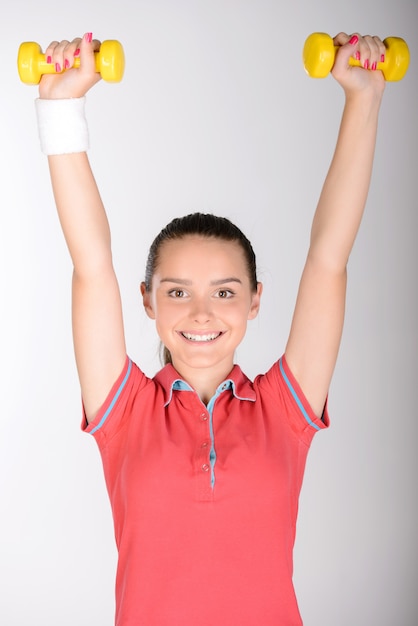 Fille qui rit en faisant de la fitness en utilisant des haltères.