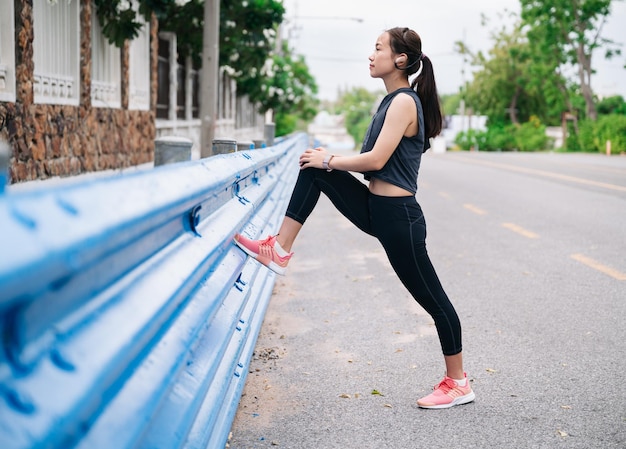 Fille qui s'étend de la jambe avant de faire du jogging