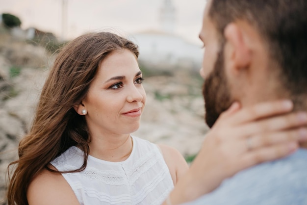 Une fille qui tient le cou de son petit ami près du phare en Espagne