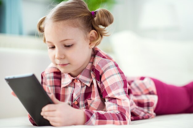 Photo une fille qui utilise une tablette numérique allongée à la maison