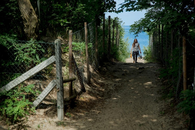 fille quittant la plage en combinaison de surf à travers la forêt