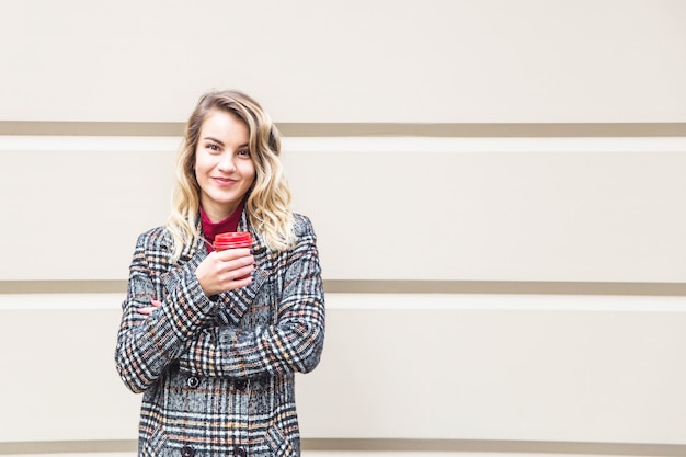 Fille de race blanche tenant une tasse rouge avec du café pour aller.