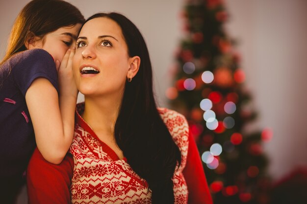 Fille racontant à sa mère un secret de Noël