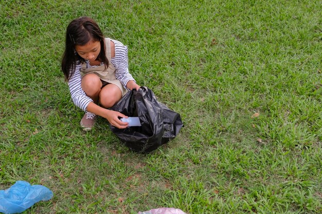 Une fille ramassant des ordures sur le champ.