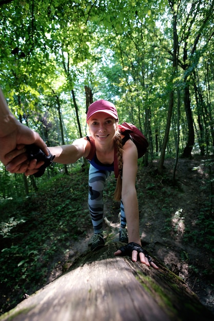 Fille de randonnée en forêt, grimper à la notation. Homme tenant la main d'une fille essayant d'aider à grimper