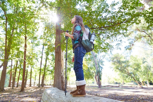 Fille de randonneur avec pôle de randonnée et sac à dos en pleine forêt