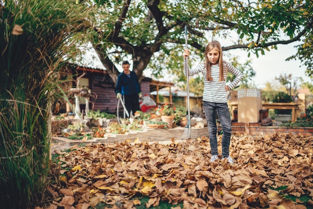 Fille ratisser les feuilles d'automne