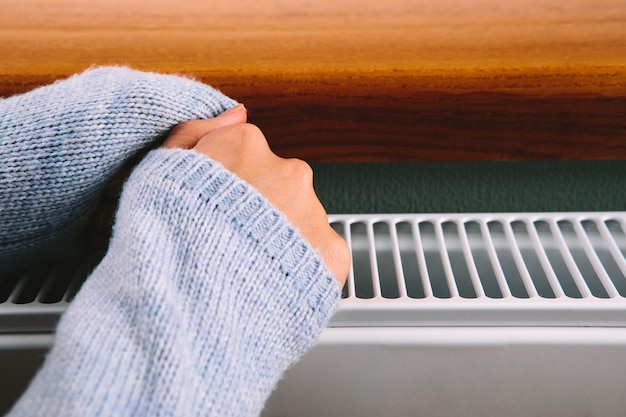 Fille réchauffe ses mains et ses pieds sur un radiateur