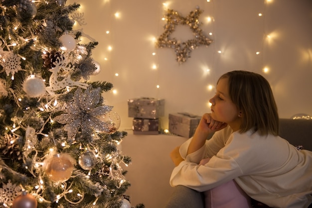 Fille réfléchie à l'arbre de Noël, tour doux