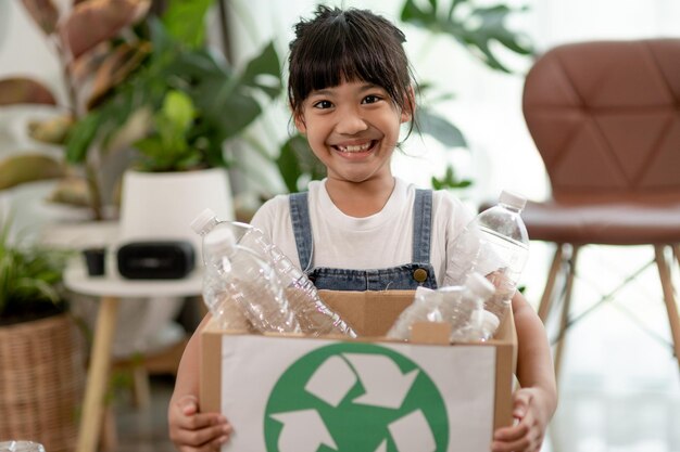 Fille regardant la caméra et tenant des bouteilles en plastique pour le recyclage