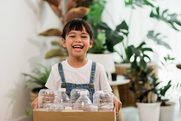 Fille regardant la caméra et tenant des bouteilles en plastique pour le recyclage