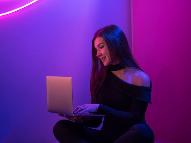 Fille regardant dans un ordinateur portable. Mur de néons