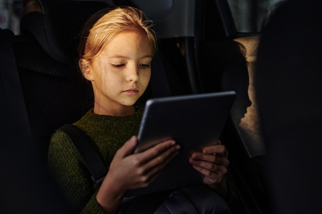 Fille regardant des dessins animés pendant le voyage en voiture