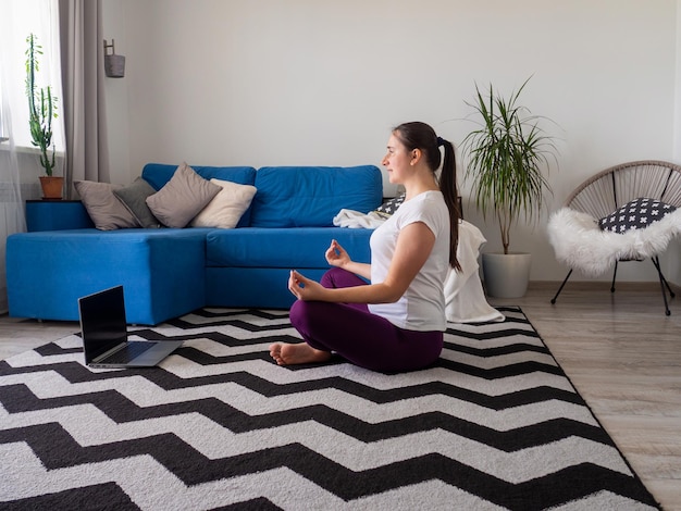 Fille regardant sur un ordinateur portable pendant la pratique du yoga à la maison