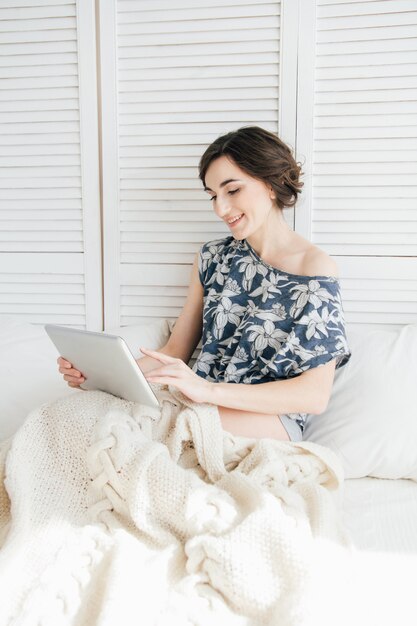 Fille regardant une tablette au lit