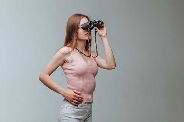 Fille Regardant à Travers Des Jumelles Sur Fond Gris