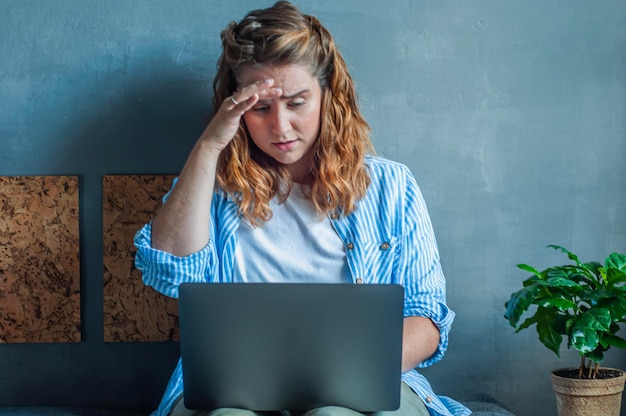 une fille regarde les actualités sur un ordinateur portable, le visage bouleversé le travail à la maison va mal les problèmes des employés à distance indépendants