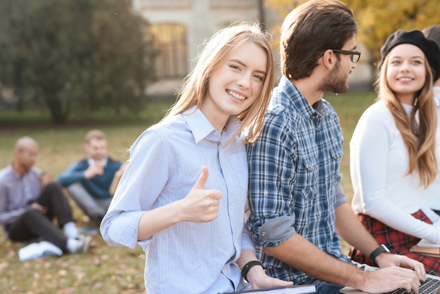 La fille regarde la caméra, assise avec des amis.