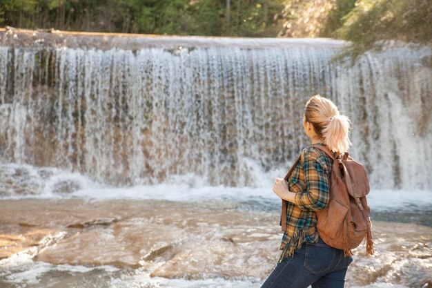 Une fille regarde une cascade un jour d'automne