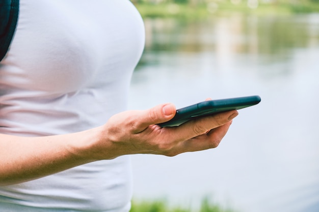 Fille regarde et lit un message sur un smartphone dans la rue.